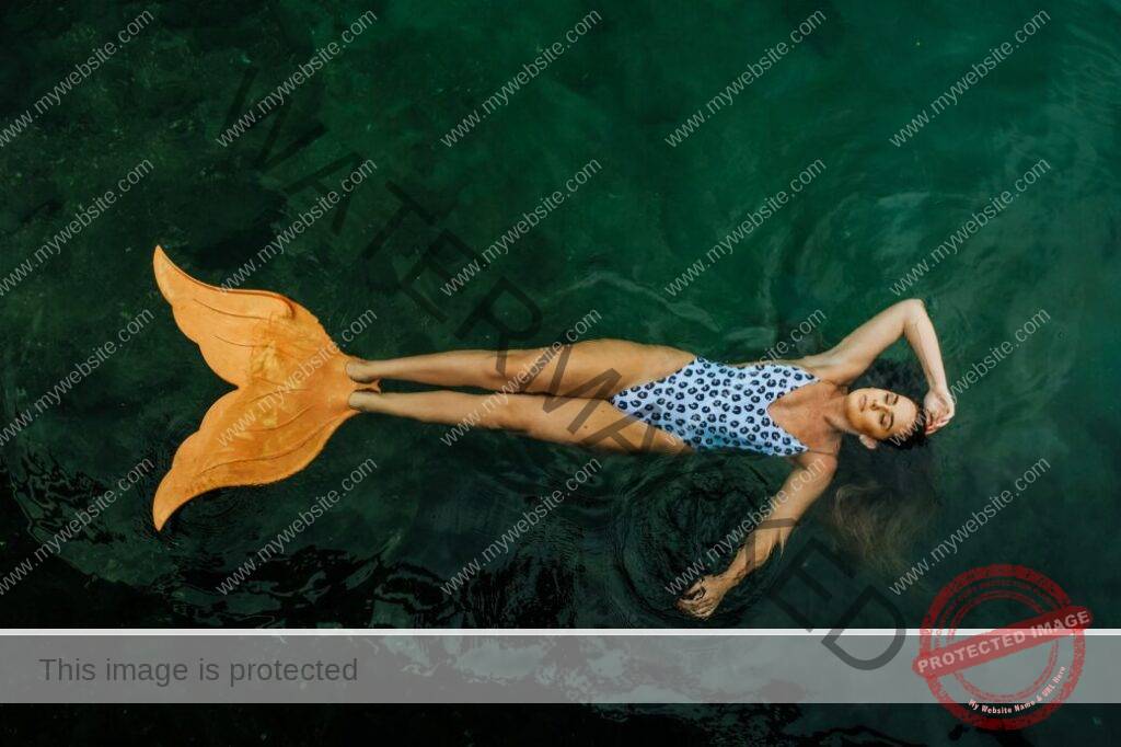 photo of woman floating on body of water with mermaid tail flippers